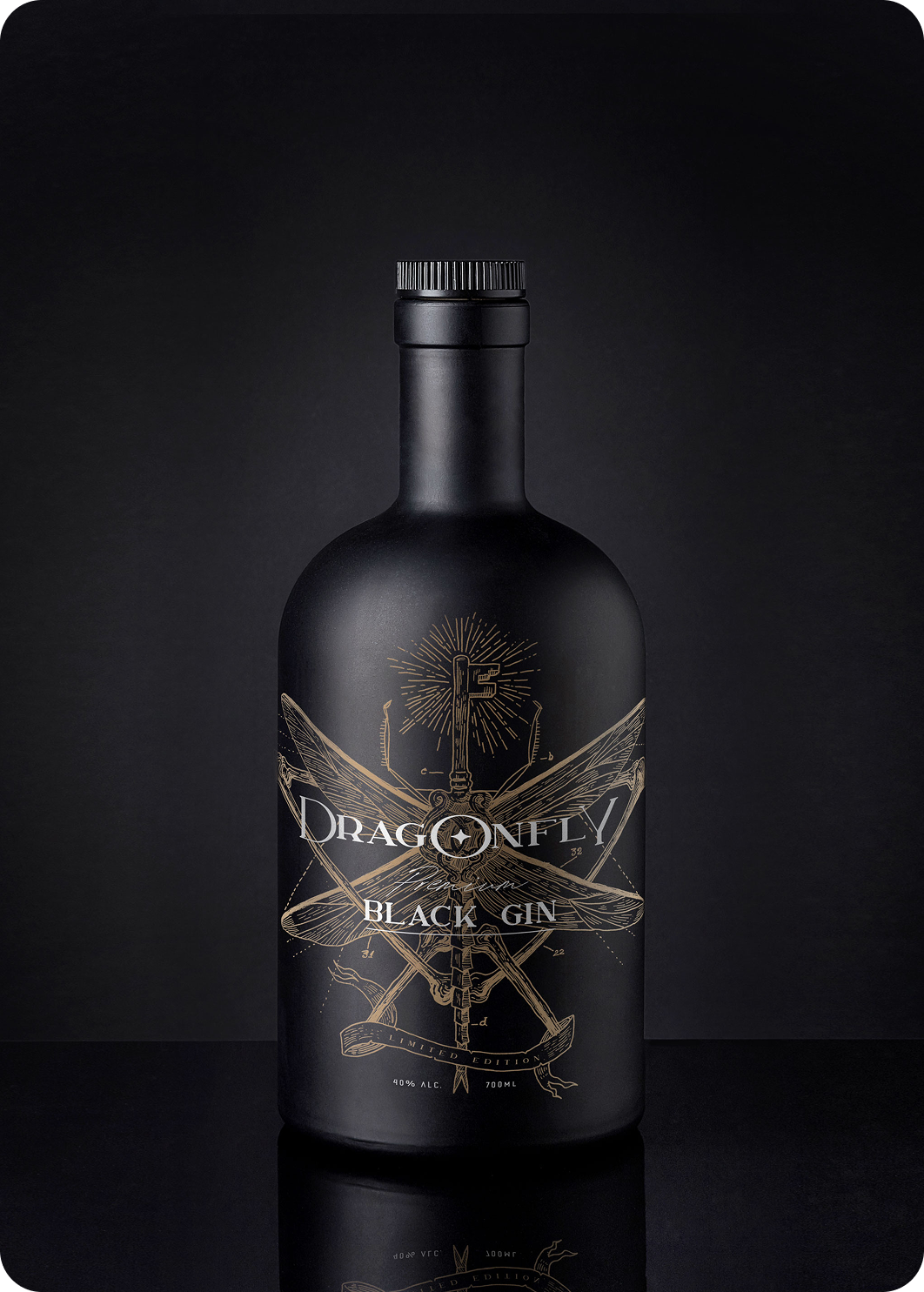Dragonfly Black Gin bottle with gold illustrated label on a dark background.